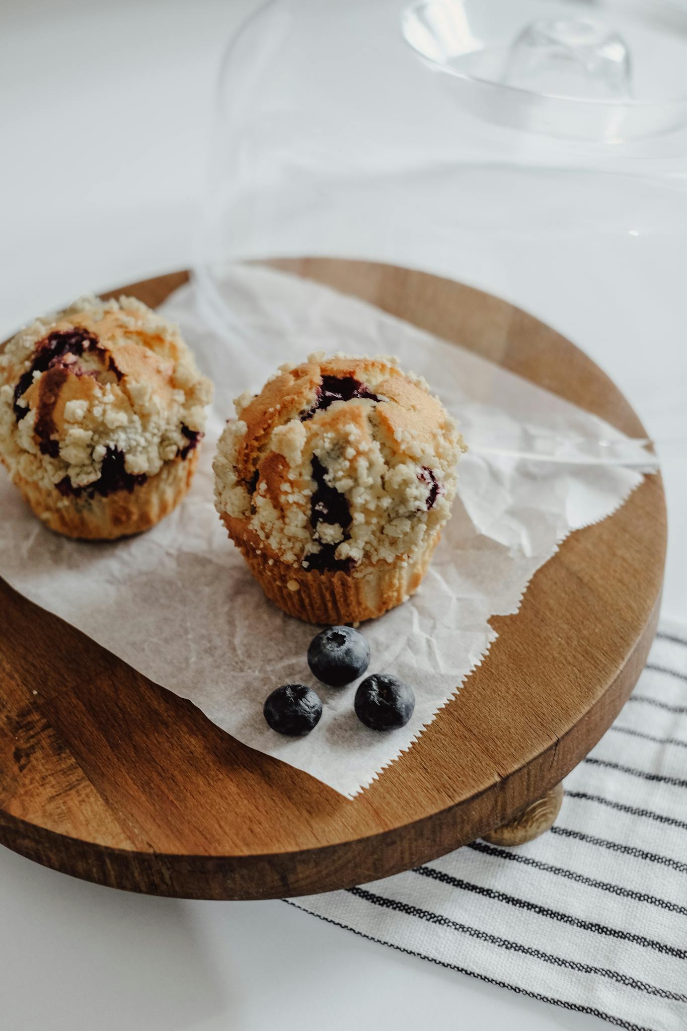 Close-up of freshly baked blueberry muffins with crumb topping on a wooden tray.